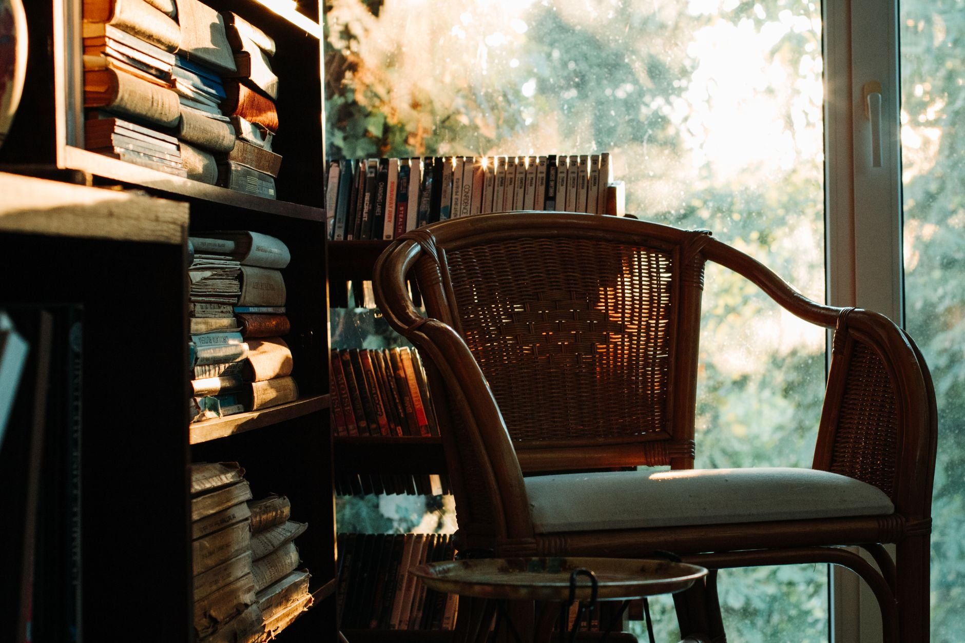 A warm, inviting reading nook with a wicker chair by a bookshelf, bathed in soft light.
